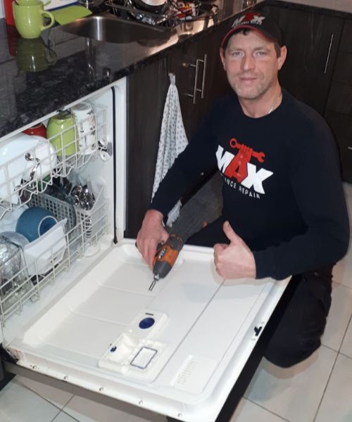 dishwasher technician next to dishwasher with tool in hand