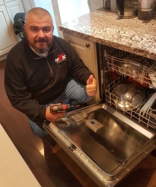 Max Appliance Repair technician posing next to fixed dishwasher