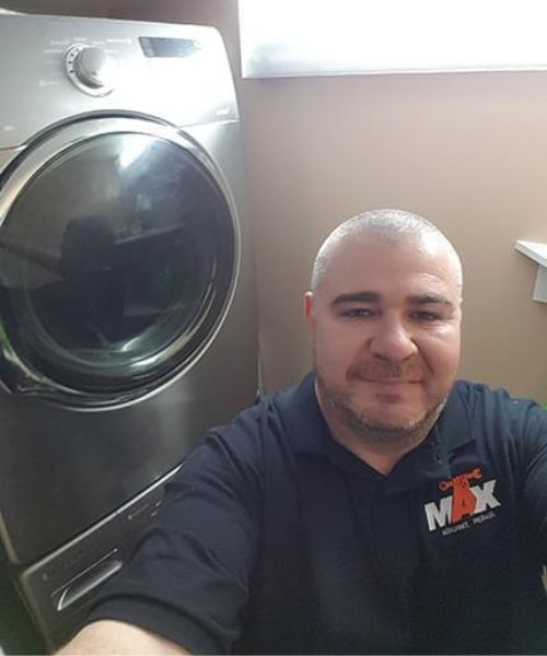 repair technician smiling next to repaired washer and dryer
